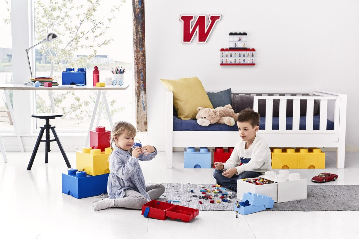 Dzieci bawiące się dużymi klockami LEGO w jasnym pokoju z pojemnikami lunchbox klocek LEGO