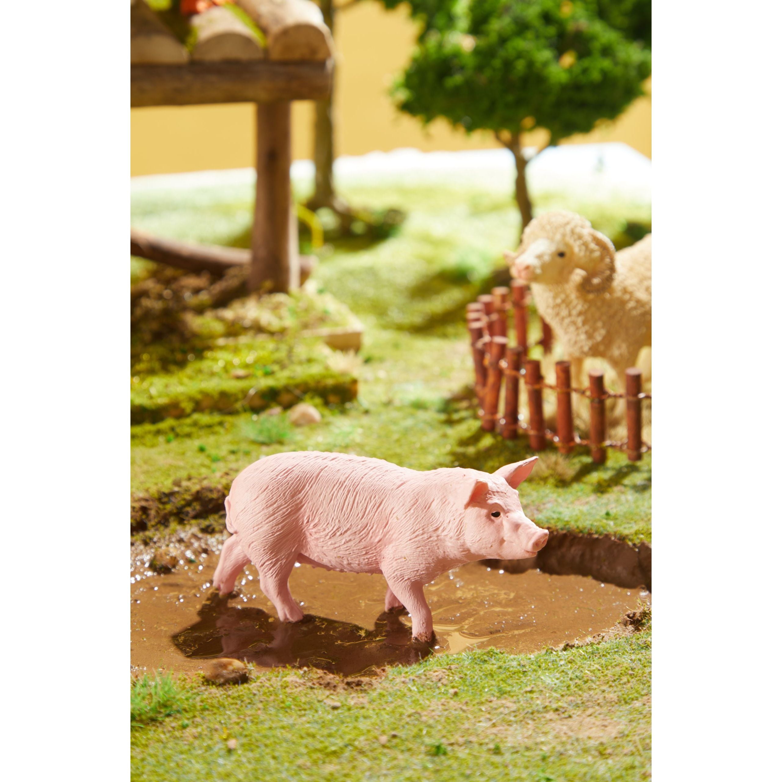 Zestaw figurek zwierząt na farmie z różową świnią na podmokłym terenie i owcą za płotem