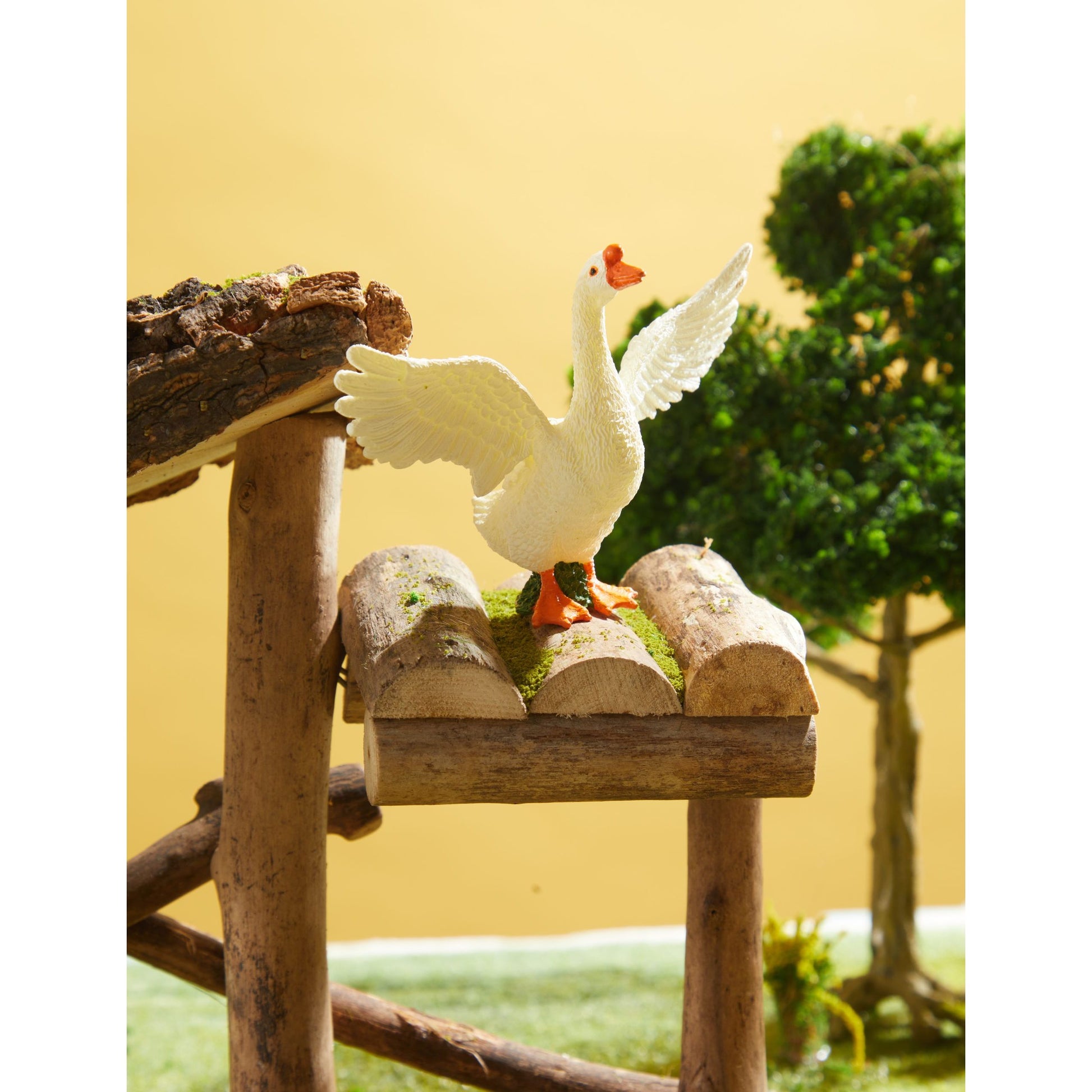 Zestaw figurek zwierząt na farmie – biała figurka gęsi rozpościerającej skrzydła na drewnianej konstrukcji