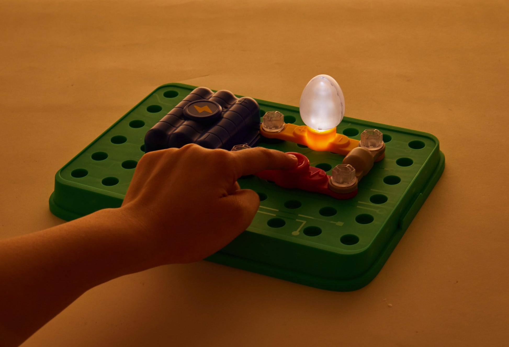 Zestaw małego inżyniera elektryka Yamann z podłączonymi elementami i świecącą żarówką na zielonej podstawce