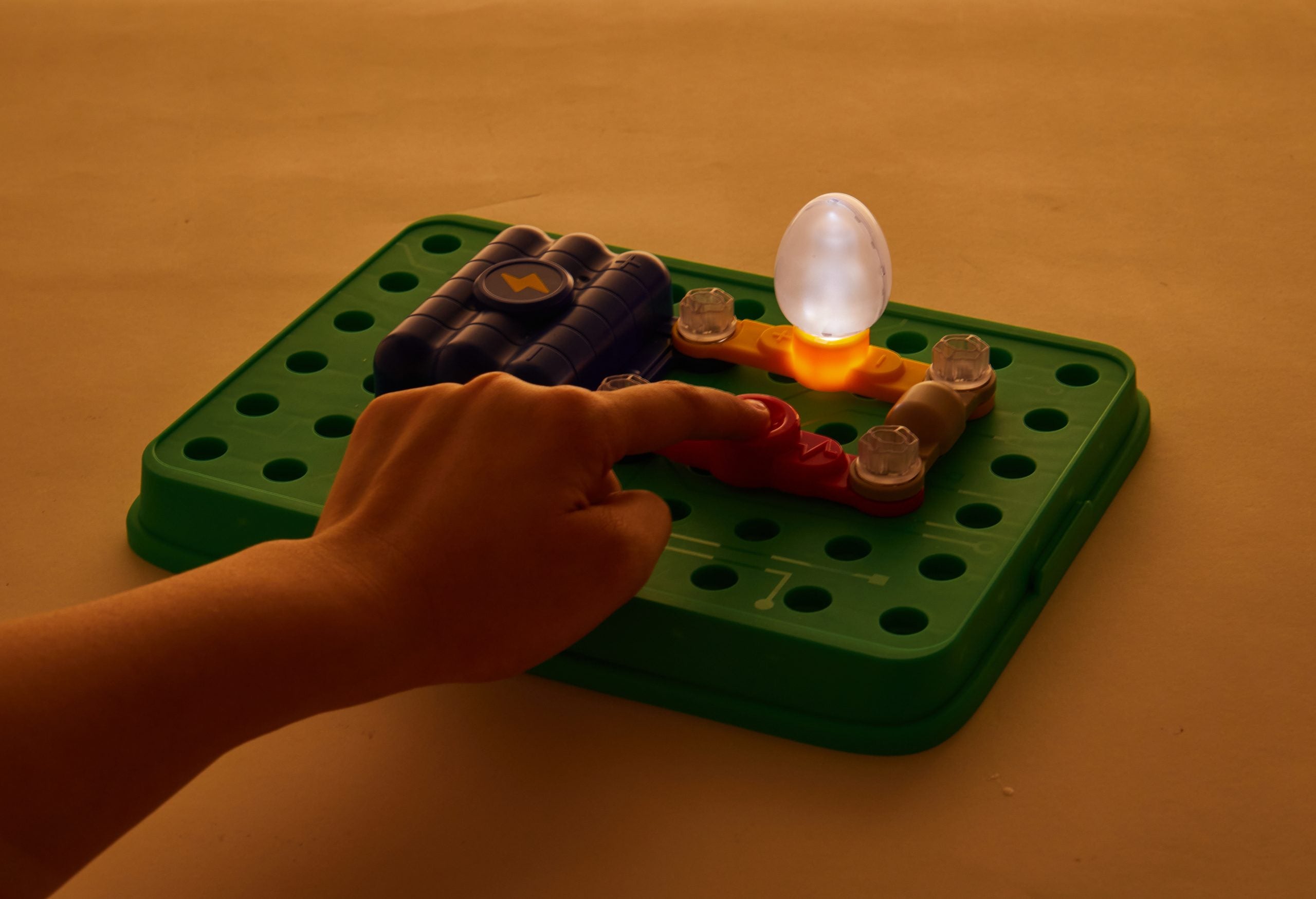 Zestaw małego inżyniera elektryka Yamann z podłączonymi elementami i świecącą żarówką na zielonej podstawce