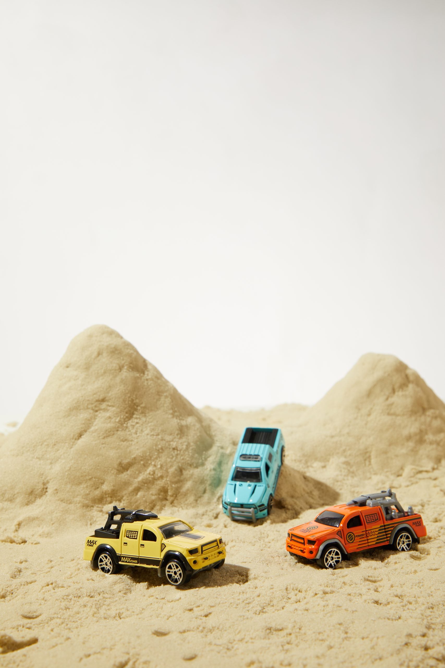 Piasek magiczny dla dzieci z trzema kolorowymi samochodzikami terenowymi i wzgórzami piasku