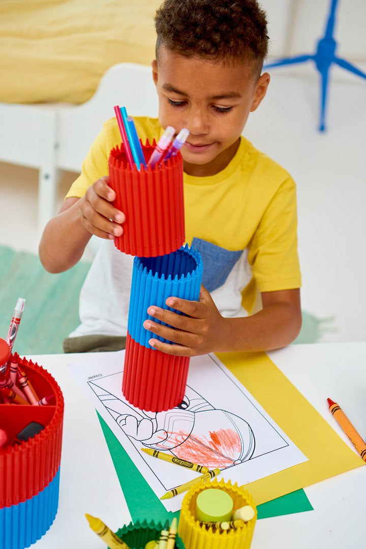 Dziecko korzystające z czerwono-niebieskiego przybornika na kredki Crayola podczas kolorowania rysunku