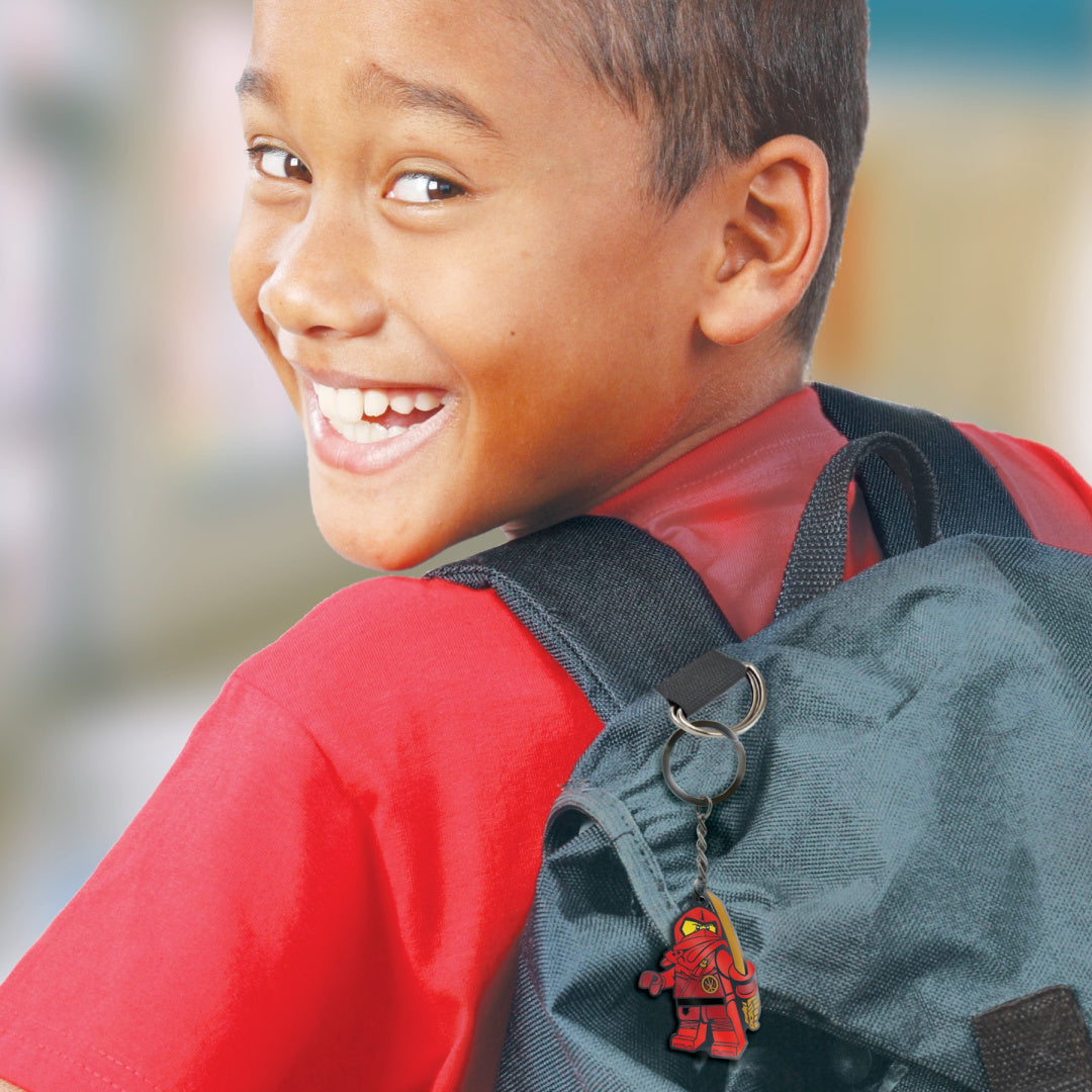 Chłopiec uśmiechnięty z plecakiem i brelok LEGO Ninjago Kai zawieszonym na pasku plecaka