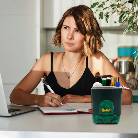 Piórnik LEGO Ninjago Lloyd z motywem zielonego ninja na biurku obok kobiety piszącej