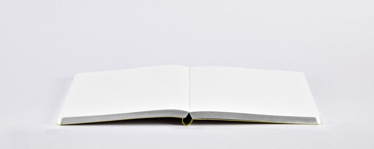 Otwarty pusty notatnik żółty firmy BV JACOB COMPANY z białymi stronami na jasnym tle