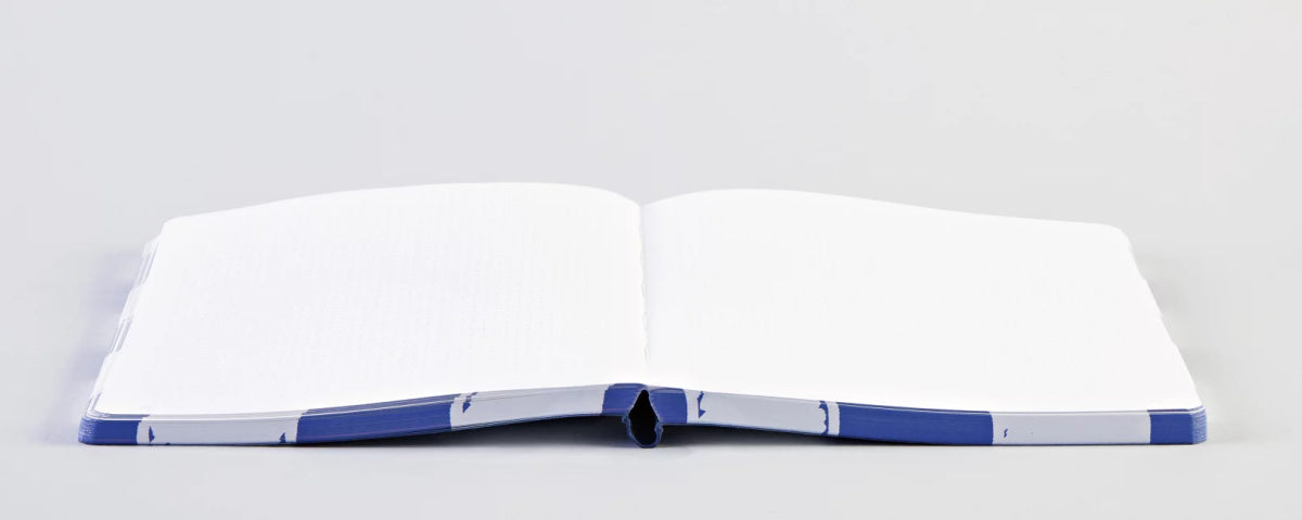 Otwarty notatnik w kratkę BV JACOB COMPANY z niebieską okładką na białym tle