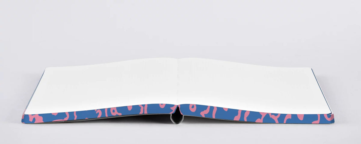 Otwarty notatnik kwiatowy z pustymi białymi stronami i kolistym wzorem na okładce