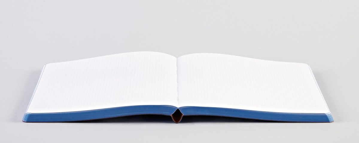 Otwarty notatnik magic idea z czystymi białymi kartkami i niebieską okładką na białym tle