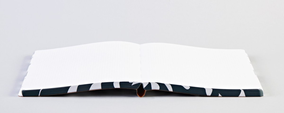 Otwart notatnik graficzny L z wzorem na okładce leżący na płaskiej powierzchni