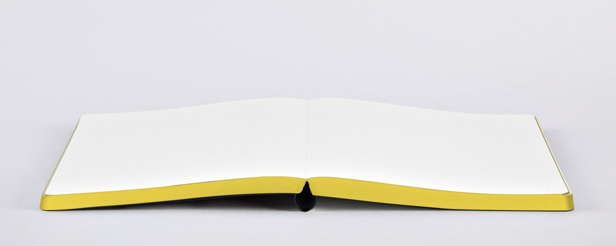 Otwarty notatnik motywacyjny z żółtymi brzegami stron na białym tle