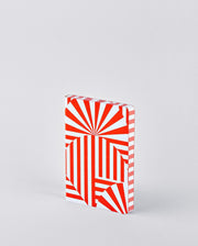 Notatnik graficzny Fancy Fans z czerwono-białym geometrycznym wzorem stojący na jasnym tle