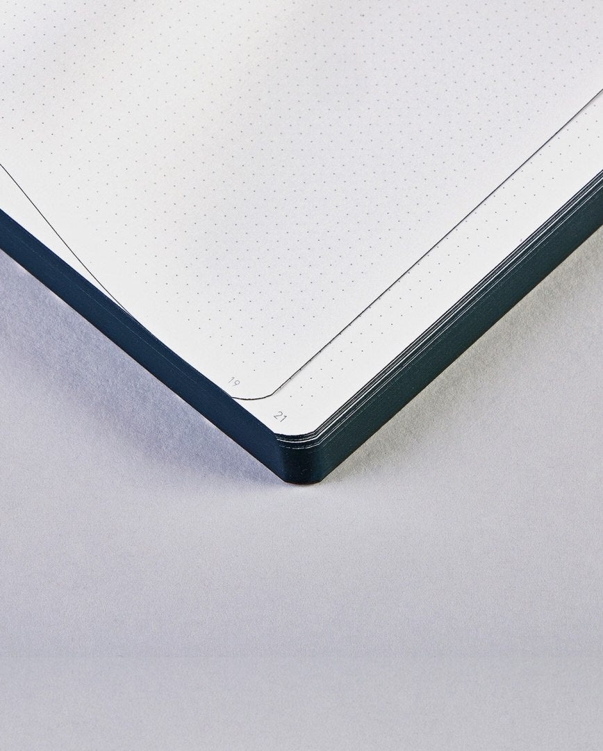 Notatnik graficzny z kropkowanymi kartkami i czarną oprawą na jasnym tle