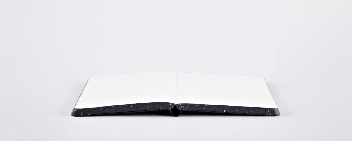 Otwarty notatnik graficzny Milky Way z czarną okładką i pustymi białymi stronami