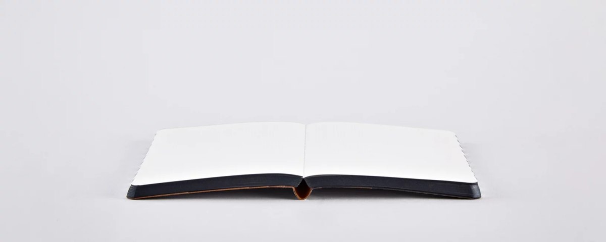 Notatnik graphic s otwarty z pustymi białymi stronami na jasnym tle