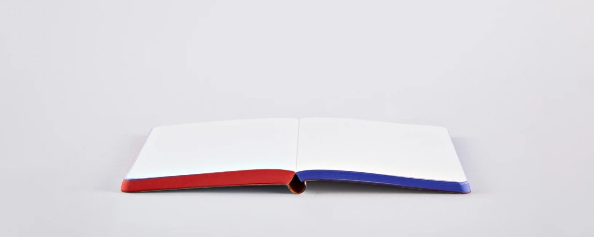 Otwarty notatnik graficzny Yes No z czerwonym i niebieskim miękkim grzbietem na białym tle