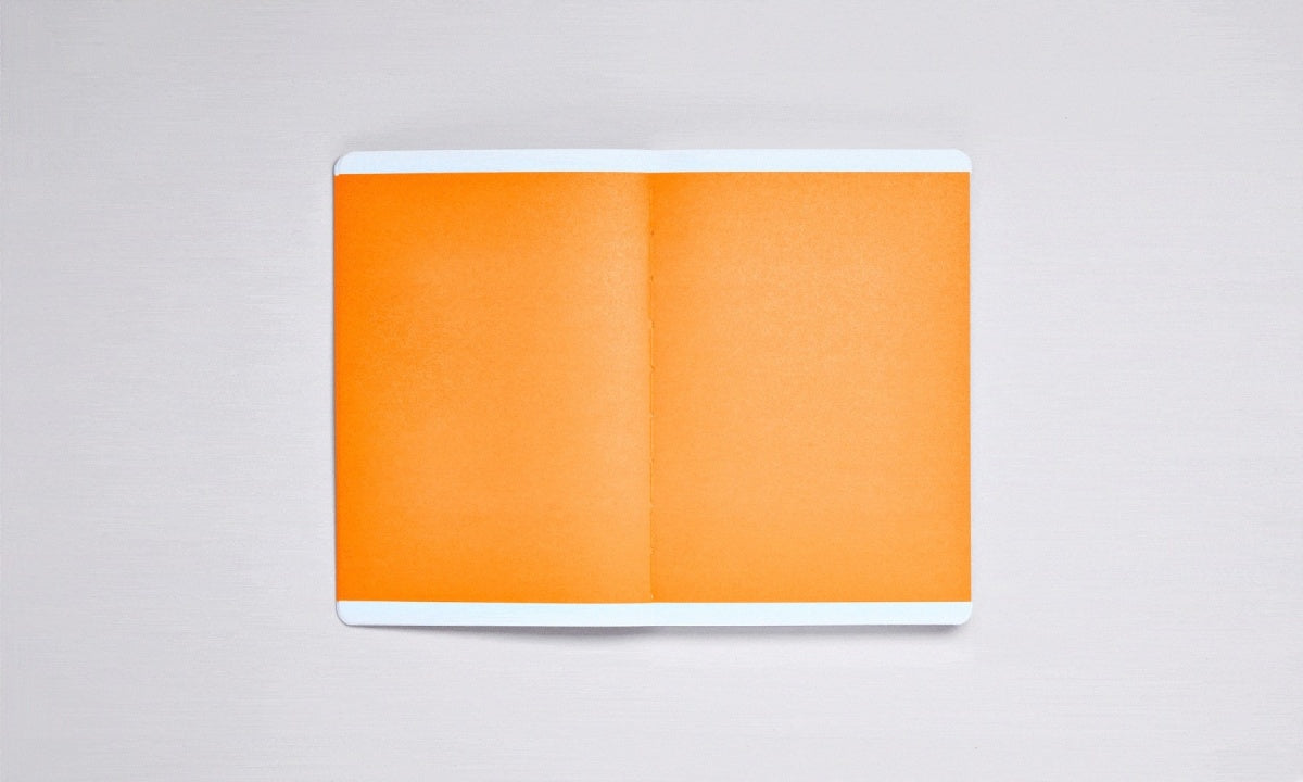 Notatnik w twardej oprawie z pomarańczowymi kartkami na jasnym tle