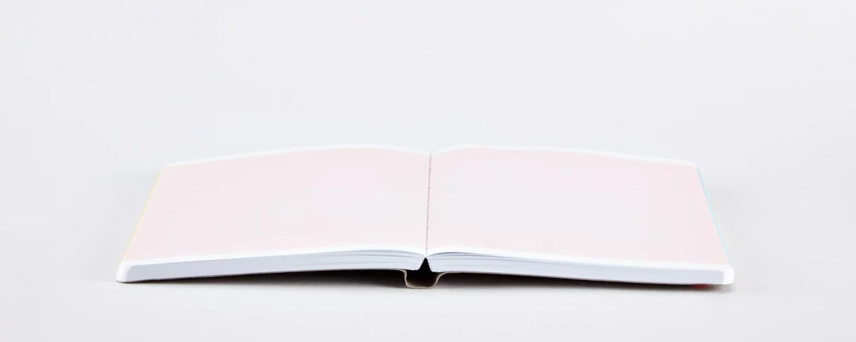 OtwartY notatnik w twardej oprawie na białym tle z pustymi różowymi stronami