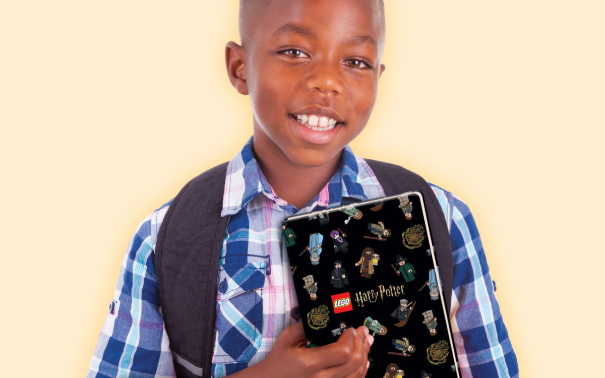 Chłopiec trzymający czarny notatnik LEGO Harry Potter z postaciami i symbolami z serii