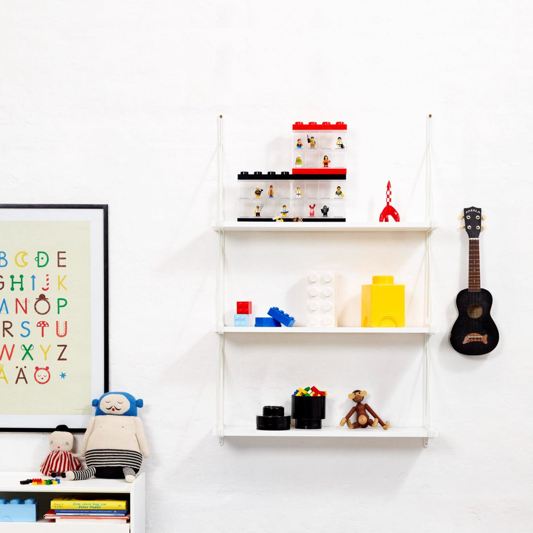 Okrągły pojemnik LEGO czarny na półce z klockami i zabawkami na białej ścianie