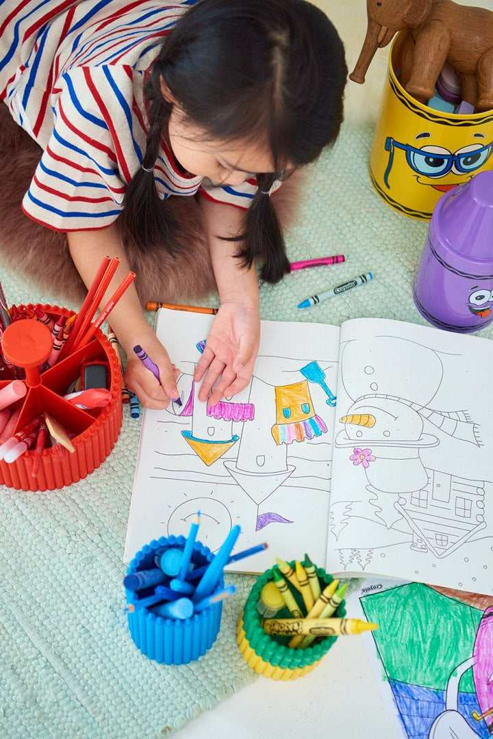 Mała dziewczynka koloruje książkę z kredkami obok czerwonego organizer na biurko Crayola różowy