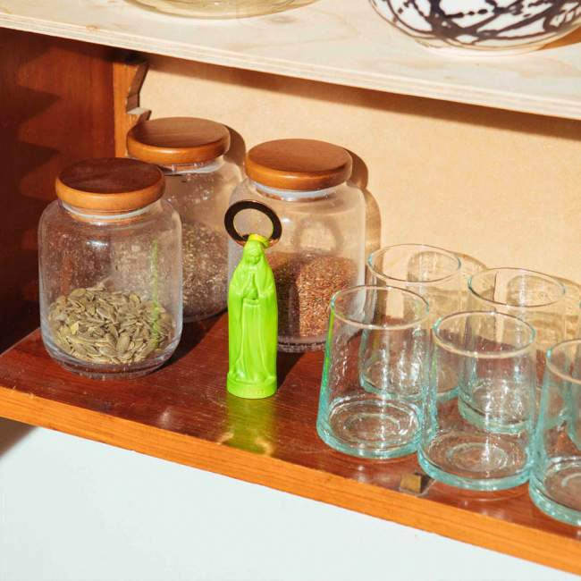 Zielony otwieracz do butelek zielony na drewnianej półce obok szklanych pojemników i szklanek