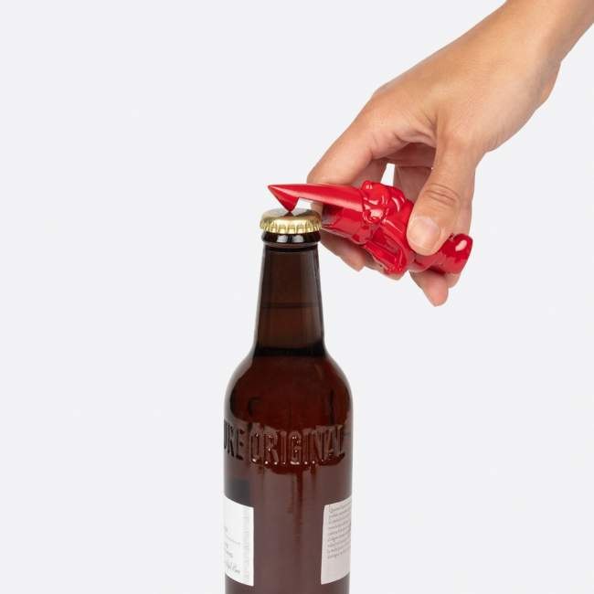 Czerwony otwieracz do butelek krasnal trzymany w ręce do otwierania butelki piwa