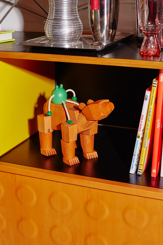 Drewniana figurka żaba zielona siedząca na drewnianym zwierzęcym modelu na półce z książkami