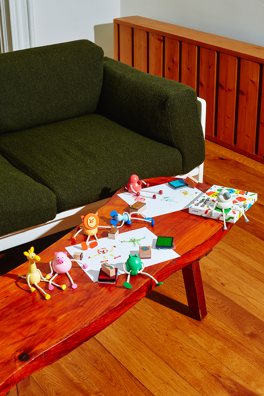 drewniana figurka żyrafa na stole obok innych kolorowych drewnianych zabawek w salonie