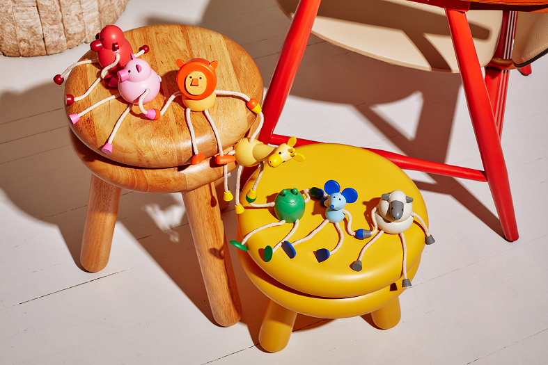 Drewniana figurka żaba i inne kolorowe drewniane zwierzątka na stołkach w dziecięcym pokoju