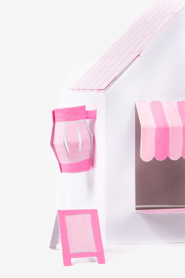 Papierowy model kawaii shop w białym kolorze z różowymi detalami, w tym markizą i manekinem