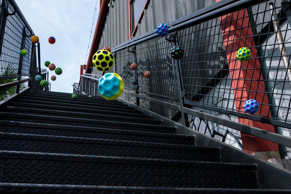 Kolorowe piłeczki Waboba Gradient Moon Ball odbijające się na metalowych schodach na świeżym powietrzu