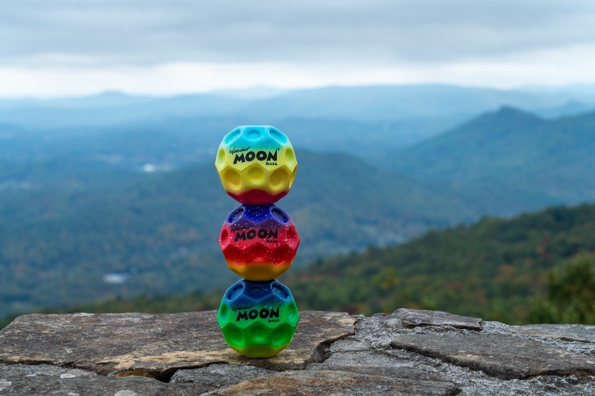Kolorowa piłeczka Waboba Gradient Moon Ball ustawiona na skałach na tle górskiego krajobrazu