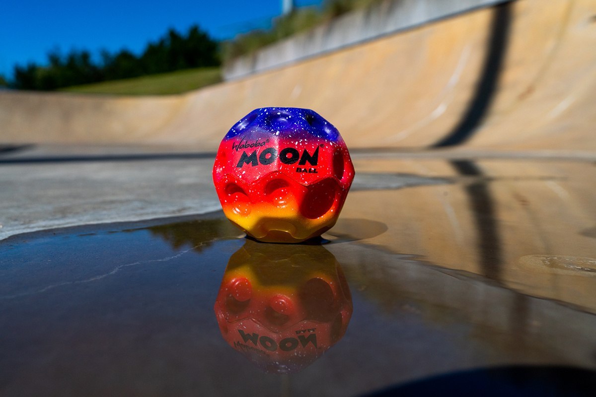 Piłeczka Waboba Gradient Moon Ball o kolorowym wzorze leżąca na mokrej powierzchni skateparku