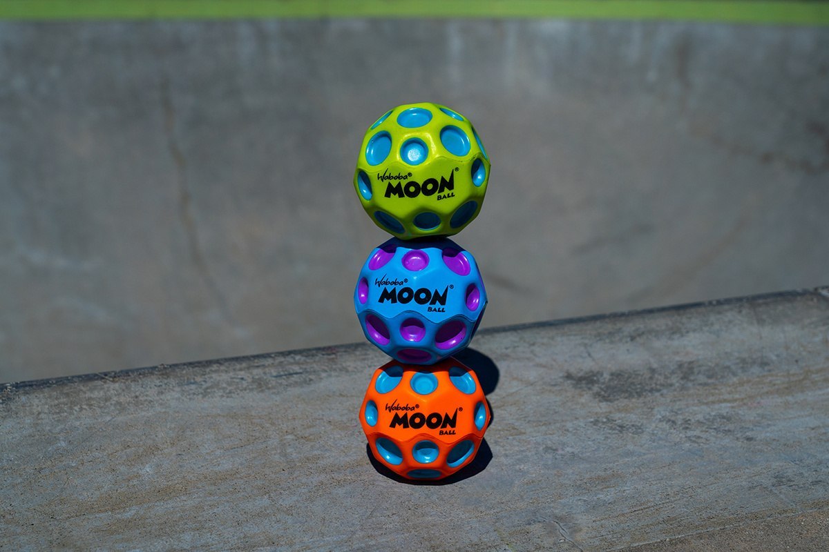 Kolorowe piłeczki Moon Ball Waboba w zielonym, niebieskim i pomarańczowym kolorze na betonowej powierzchni