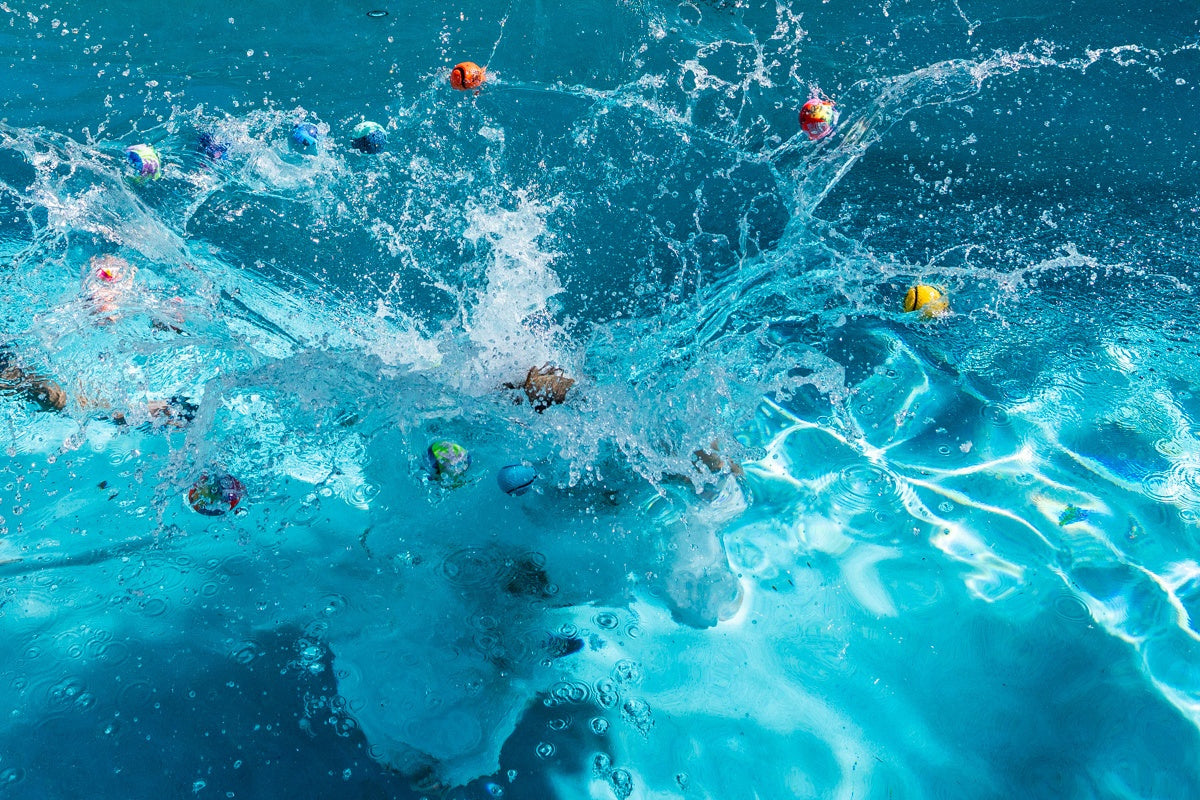 Kolorowe piłeczki Waboba Original odbijające się na powierzchni wody podczas zabawy w basenie