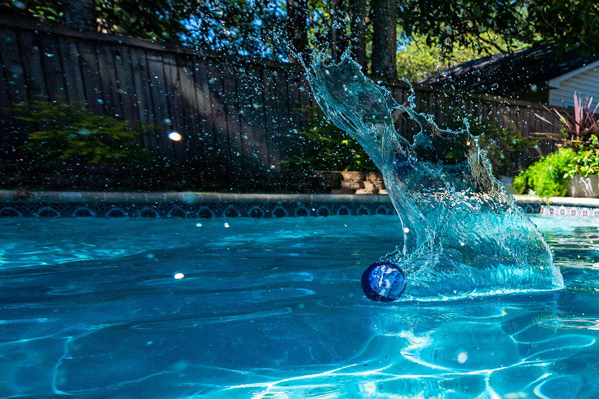 Niebieska piłeczka Waboba Original odbijająca się na wodzie basenu podczas zabawy
