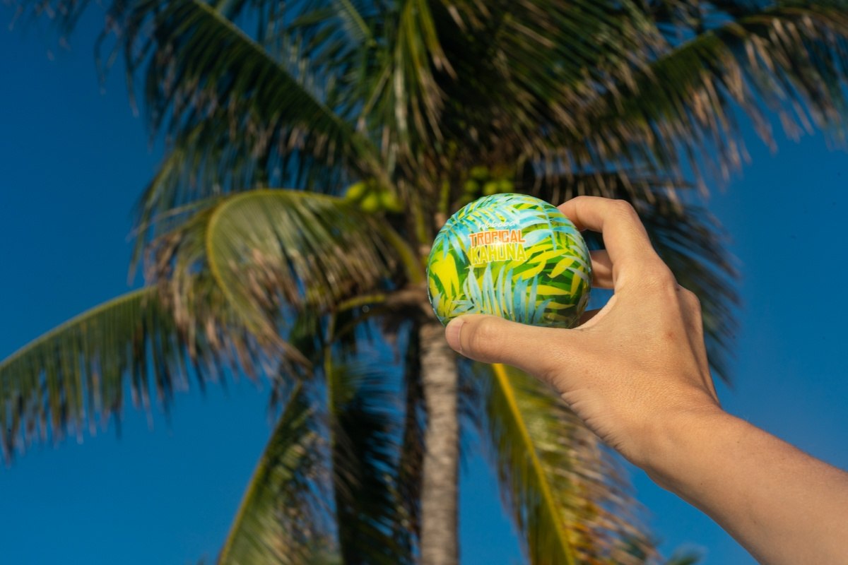 Piłka na wodę Waboba Tropical Kahuna w ręce na tle palmy i błękitnego nieba