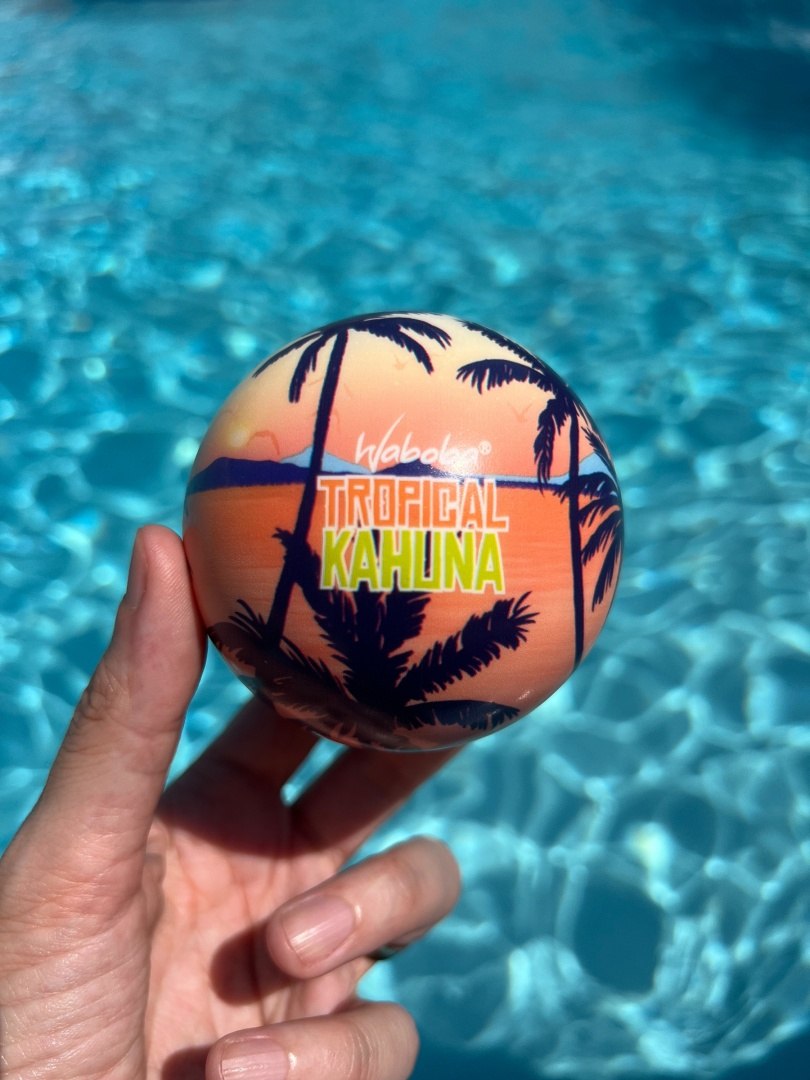 Piłka na wodę Waboba Tropical Kahuna z tropikalnym wzorem trzymana nad basenem