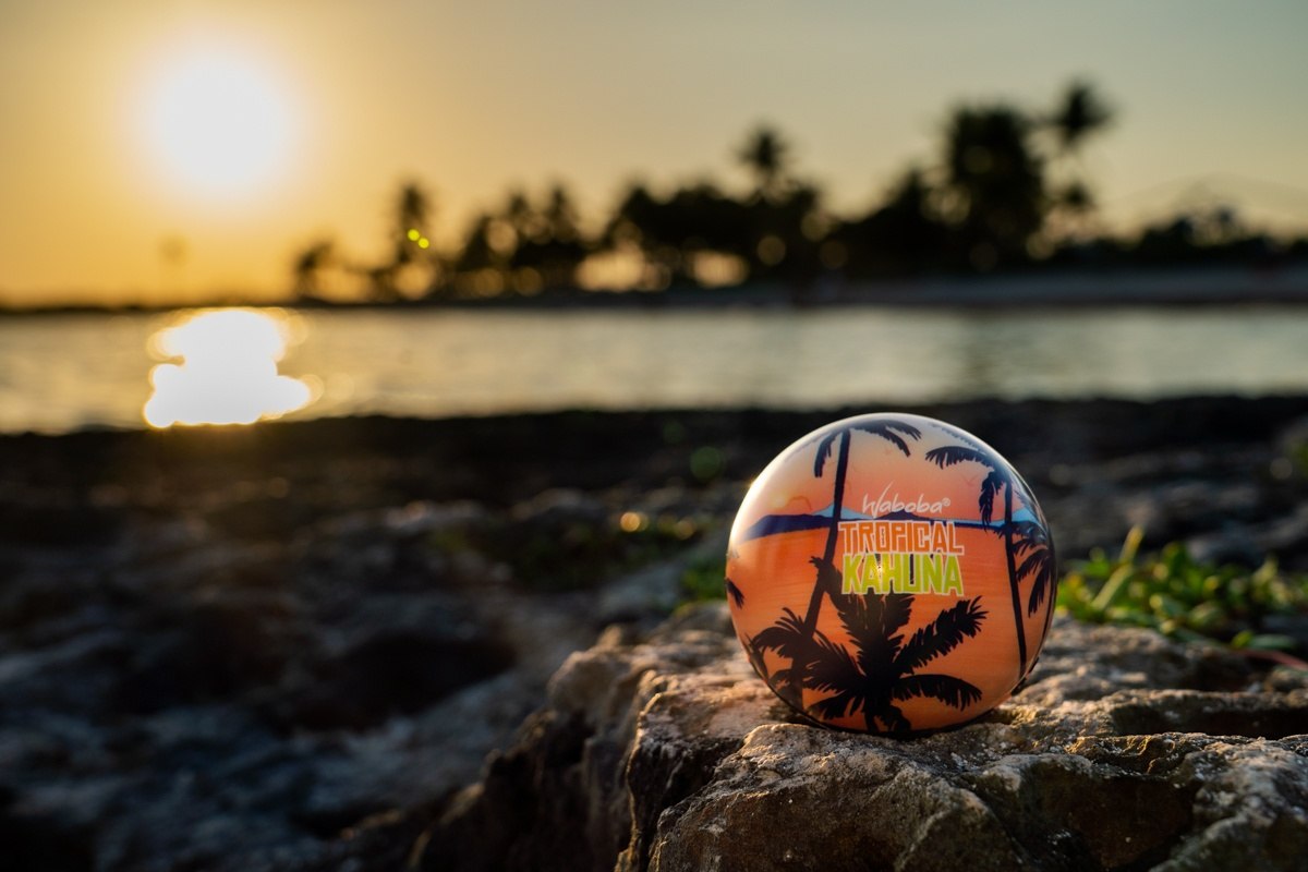 Piłka na wodę Waboba Tropical Kahuna z palmami na pomarańczowym tle na kamieniach przy zachodzie słońca