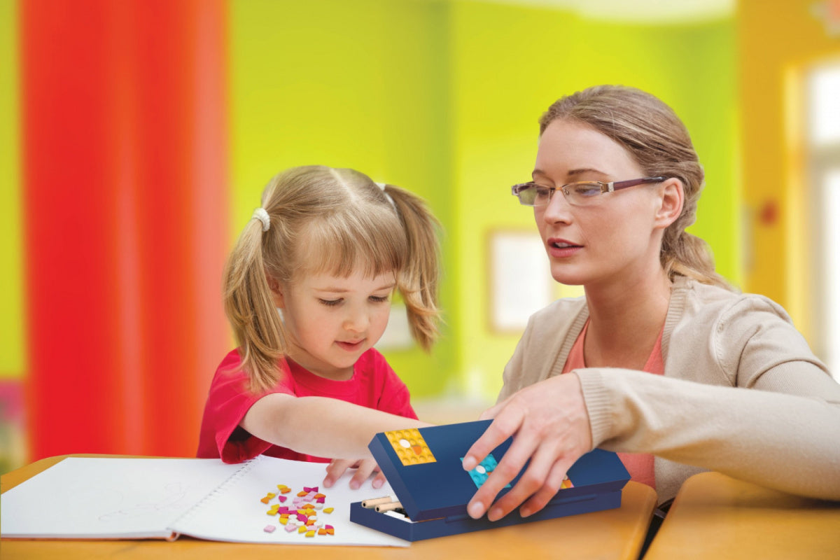 Dziecko i dorosły bawią się piórnikiem LEGO DOTS dla dzieci z kolorowymi elementami na stole