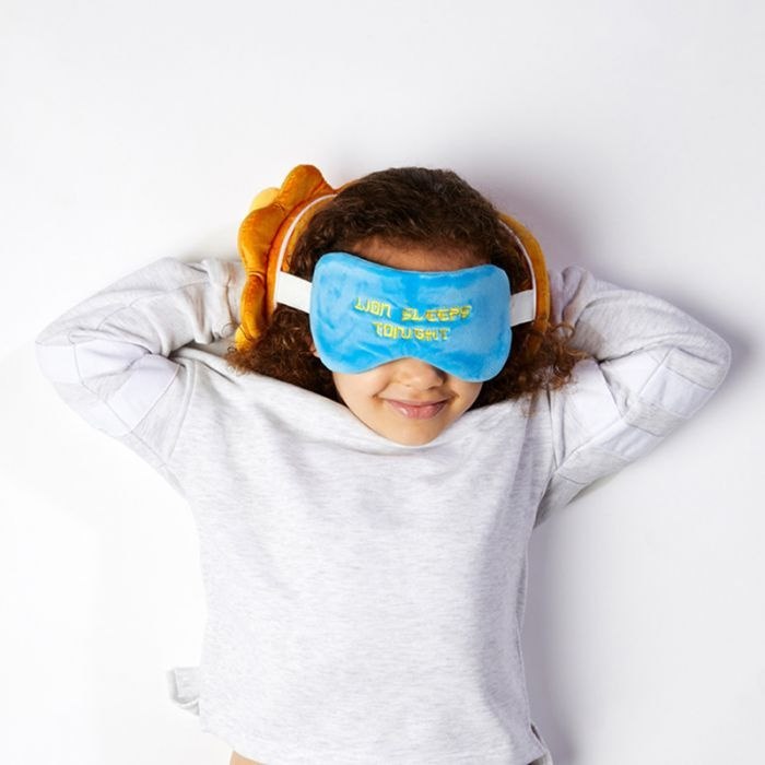 Pluszowa poduszka podróżna z opaską na oczy w niebieskim kolorze na dziecku leżącym na plecach