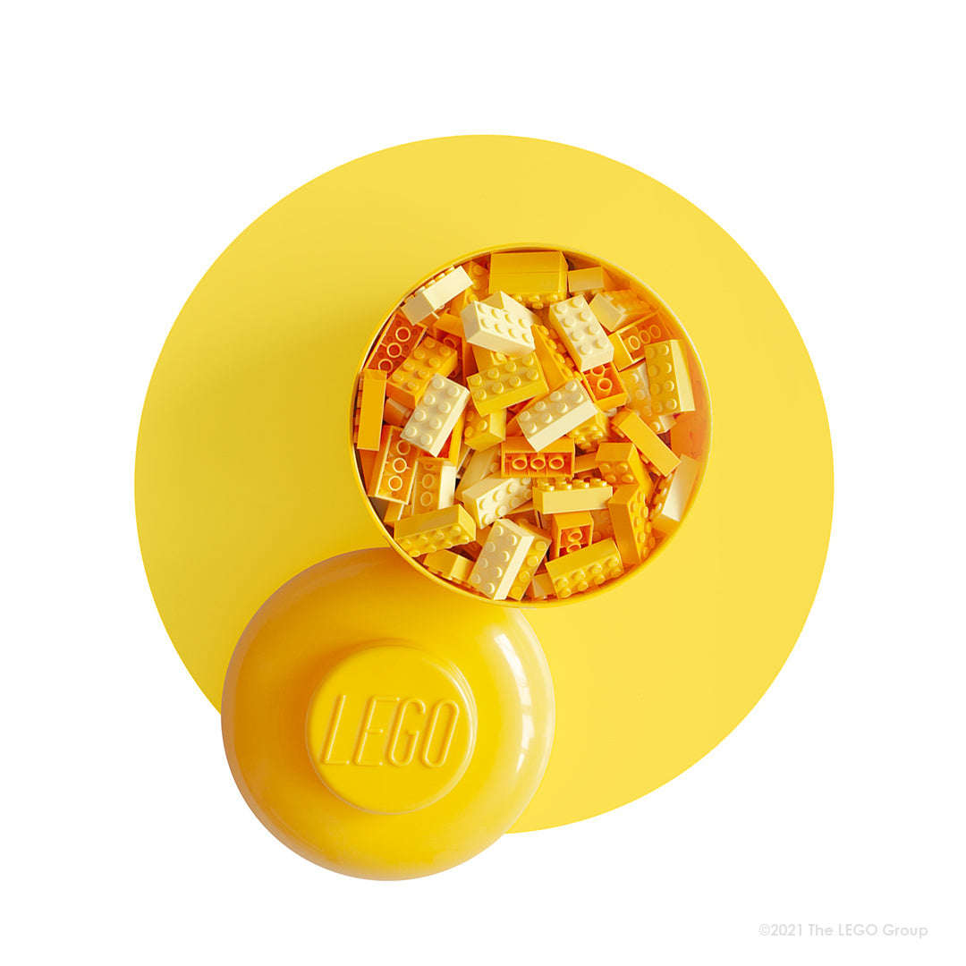 Żółty pojemnik LEGO dziewczynka z logo Lego wypełniony pomarańczowymi i żółtymi klockami