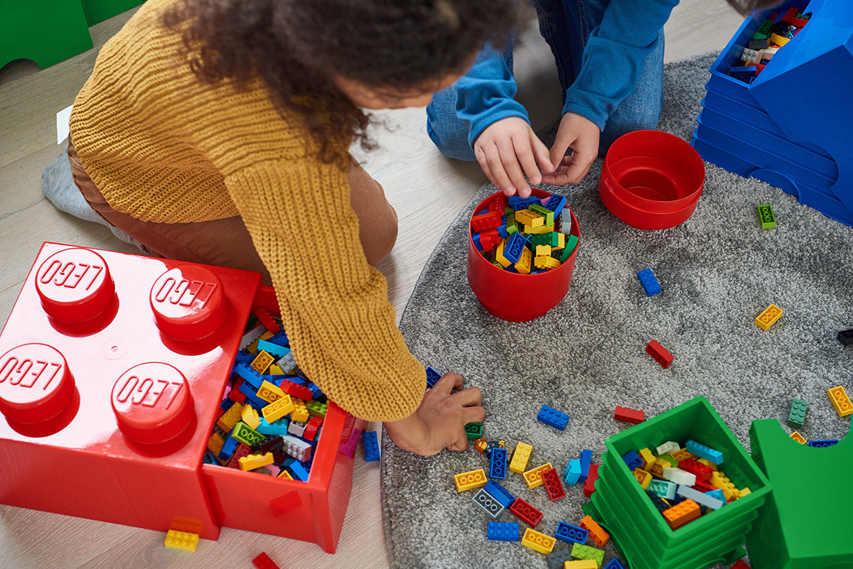 Dzieci bawiące się klockami z pojemnikiem LEGO zielony i innymi pojemnikami na zabawki