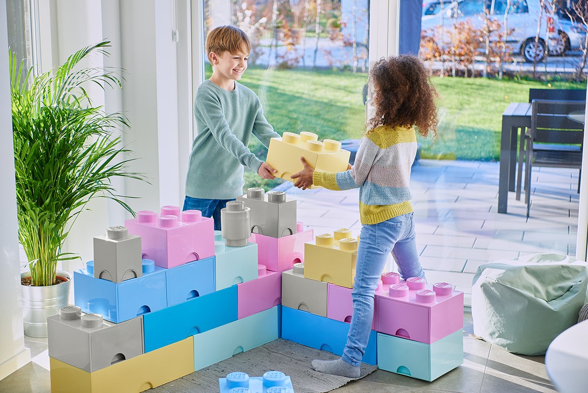 Dzieci bawiące się dużymi klockami z pojemnikiem LEGO jasnoniebieskim w jasnym salonie