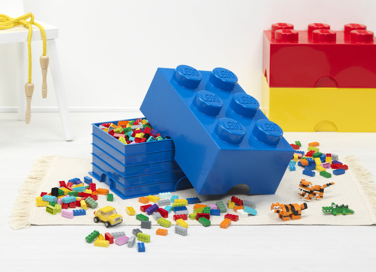 Pojemnik LEGO na zabawki w kształcie niebieskiej kostki z kolorowymi klockami LEGO wokół