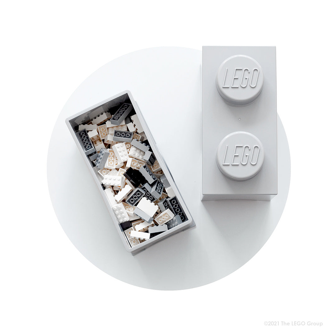 Szary pojemnik LEGO Brick szary w kształcie klocka z logo LEGO na wieczku zawierający białe i czarne klocki