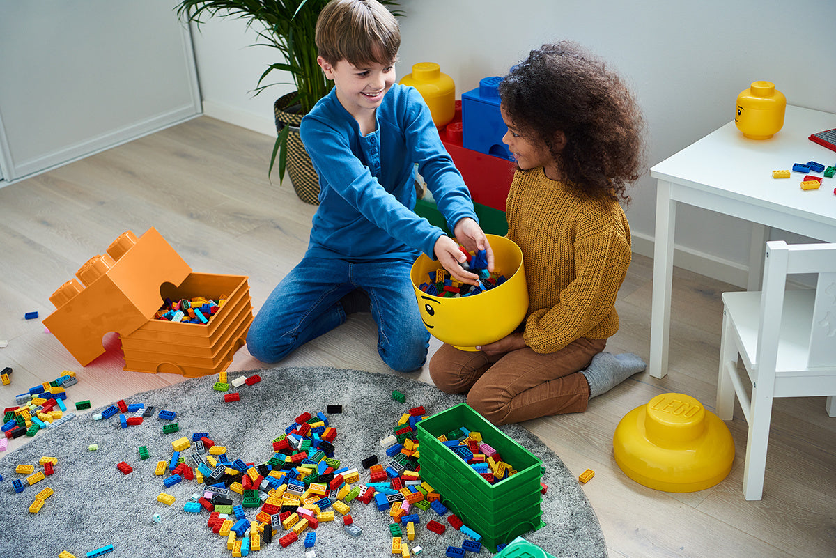 Dzieci bawiące się klockami LEGO z kolorowym pojemnikiem LEGO na zabawki w pokoju