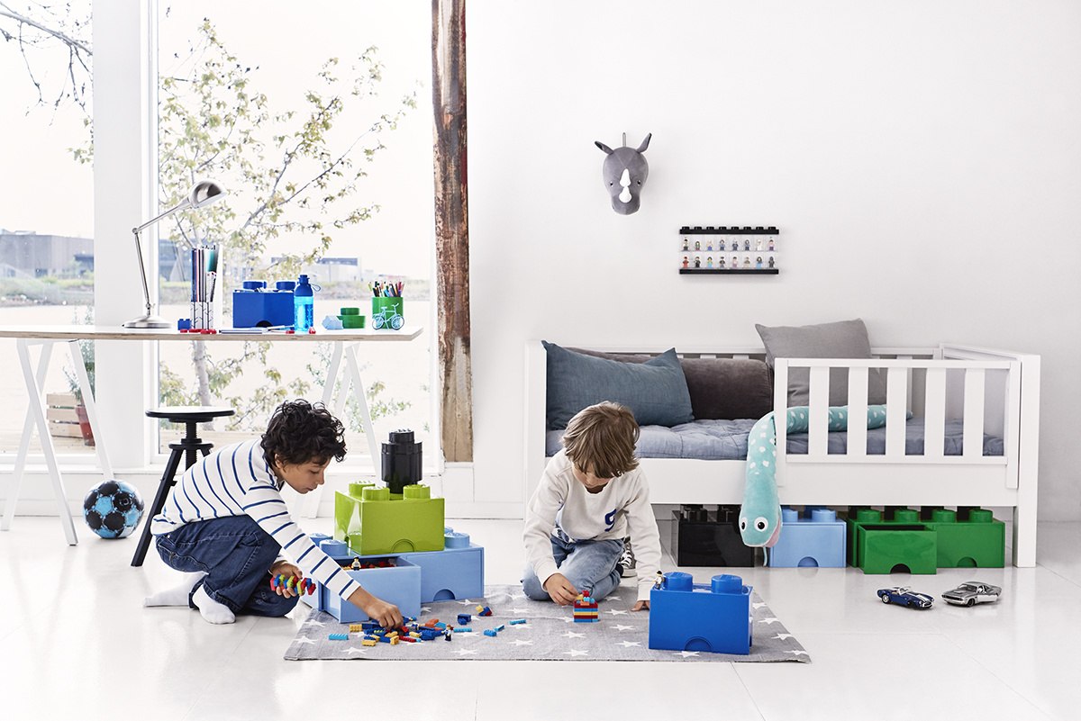 Pojemnik LEGO jasny zielony z dużymi klockami na podłodze pokoju dziecięcego z dwoma bawiącymi się dziećmi