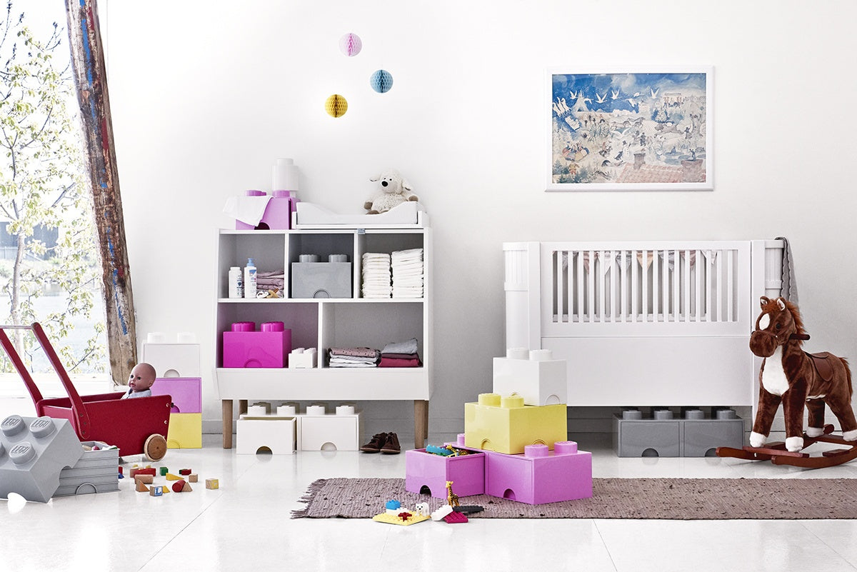 Pojemnik LEGO różowy w pokoju dziecięcym na zabawki i klocki obok białych mebli i konika na biegunach